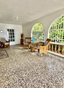 a living room with chairs and a table and two windows at Casa Nube in Cayey