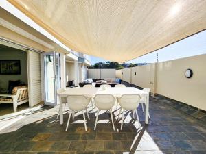 ein weißer Tisch und Stühle auf einer Terrasse in der Unterkunft Central Beach Stay Ultimate Holiday Spot in Jeffreys Bay