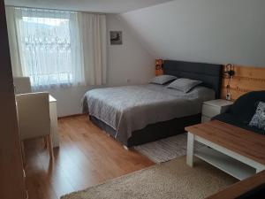 a bedroom with a bed and a window and a table at Ubytovanie Otília in Zuberec