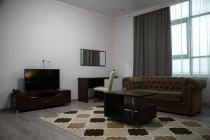 a living room with a couch and a flat screen tv at Baitau Hotel Aktobe in Aktobe