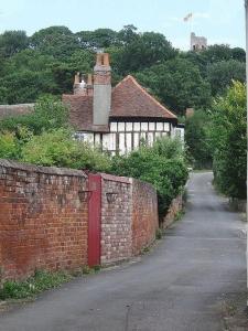 un mur en briques avec une porte en face d'une maison dans l'établissement Beautiful Cottage opposite Hedingham Castle!, à Castle Hedingham