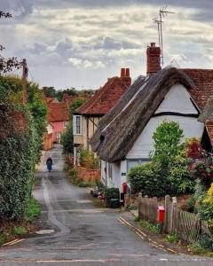 une maison au toit de chaume dans une rue de village dans l'établissement Beautiful Cottage opposite Hedingham Castle!, à Castle Hedingham