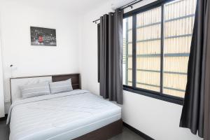 une chambre avec un lit et une grande fenêtre dans l'établissement London House Phuket, à Kata Beach