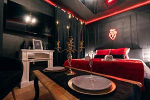 Cette chambre comprend une table et un lit avec un canapé rouge. dans l'établissement Love room - Le secret du marquis, à Provins