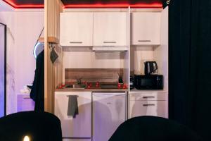 une petite cuisine avec des armoires blanches et un évier dans l'établissement Love room - Le secret du marquis, à Provins