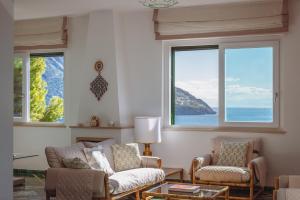 a living room with two chairs and two windows at POSEA Collection - Villa La Nice in Positano