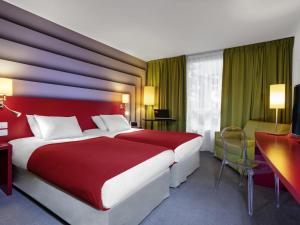 a hotel room with a red bed and a desk at ibis Styles Avignon Sud in Avignon