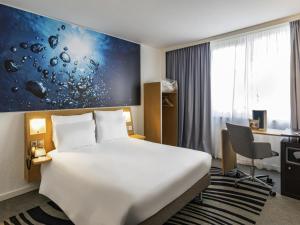 ein Hotelzimmer mit Bett und Schreibtisch in der Unterkunft Hotel Novotel Evry Courcouronnes in Courcouronnes