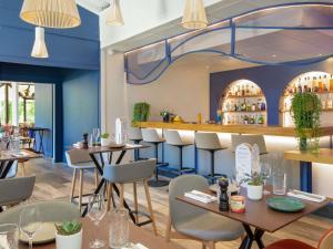 a restaurant with blue walls and tables and chairs at Novotel Aix-en-Provence Pont de L'Arc in Aix-en-Provence