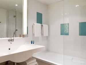 Un baño blanco con lavabo y ducha en Novotel Rouen Sud Zenith Parc Expo, en Saint-Étienne-du-Rouvray