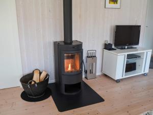 a wood stove in a living room with a television at 6 person holiday home in Løkken in Løkken +15 photos