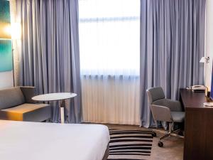 a hotel room with a bed and a desk and a window at Novotel Lyon Bron Meeting & Events in Bron