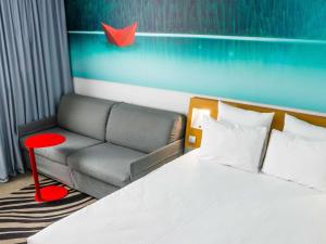 a bedroom with a bed and a couch and a chair at Novotel Lyon Bron Meeting & Events in Bron +139 photos