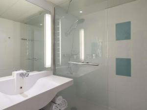 a white bathroom with a sink and a shower at Novotel Lyon Bron Meeting & Events in Bron