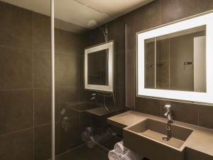 a bathroom with a sink and a mirror at Novotel Lyon Bron Meeting & Events in Bron