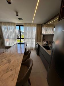 a kitchen with a long counter and chairs in it at RCM Vilas - Studio H Sunrise in Boa Vista