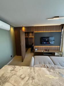 a living room with a couch and a tv on a wall at RCM Vilas - Studio H Sunrise in Boa Vista