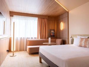 a hotel room with a bed and a couch at Novotel Toulouse Purpan Aéroport in Toulouse