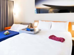 Una habitación de hotel con una gran cama blanca con una almohada encima. en ibis Styles Marseille Aéroport, en Vitrolles 50 fotos más