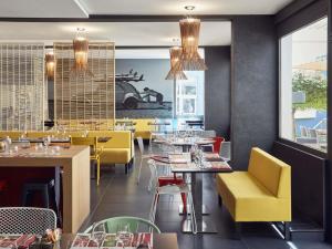 a restaurant with yellow chairs and tables in a restaurant at Ibis styles Toulon la Seyne sur Mer in La Seyne-sur-Mer
