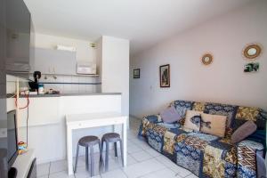 ein Wohnzimmer mit einer Couch und zwei Hockern in der Unterkunft Chez Juan - T3 Climatisé - Piscine et parking in Sète + 5 Fotos