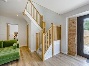 ein Wohnzimmer mit einer Treppe und einer grünen Couch in der Unterkunft The Stone Barn 