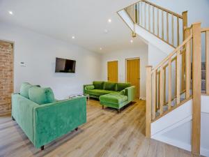 ein Wohnzimmer mit 2 grünen Stühlen und einer Treppe in der Unterkunft The Stone Barn 