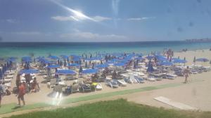 a beach with chairs and blue umbrellas and people at Appartamento al mare, Isola blu in Marzamemi