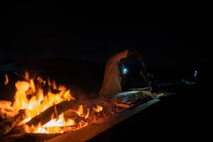 a campfire with a person standing next to it at Soléi Desert Retreat in Siwa