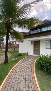 einen Backsteinsteg vor einem Haus mit einer Palme in der Unterkunft Bangalô - Beach Class Resort - Praia Muro Alto - Porto de Galinhas - by HomeTemp in Porto De Galinhas
