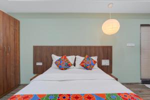 een slaapkamer met een groot wit bed met kleurrijke kussens bij FabHotel Morning Glory in Bangalore