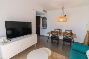 Una sala de estar con un televisor grande y una mesa. en Bella Palace, Apartamento acogedor junto al mar, en Alcanar