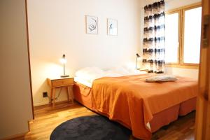 une chambre avec un lit avec une couverture orange dans l'établissement Luosto Villa D, à Luosto
