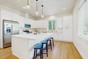 a white kitchen with white cabinets and blue stools at Lake Goodwin Retreat in Lake Goodwin