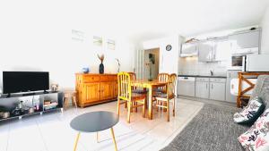 a living room with a table and a kitchen at L'air de Stella-Plage au coeur de la Station Balnéaire in Stella-Plage