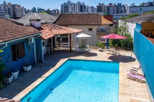 a blue swimming pool in a yard with buildings at hostel Rep MADAGASCAR in Florianópolis