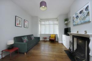 ein Wohnzimmer mit einer grünen Couch und einem Kamin in der Unterkunft West London Home in Ealing