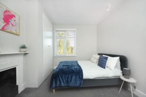 ein weißes Schlafzimmer mit einem Bett und einem Kamin in der Unterkunft West London Home in Ealing