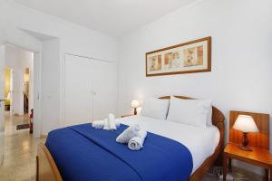 a bedroom with a blue and white bed with towels on it at Happy House Central Apartment in Faro