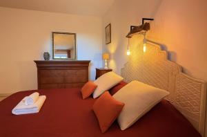 a bedroom with a bed with red sheets and orange pillows at Le Clos de Vinzelle 12personnes Piscine in Vinzelles