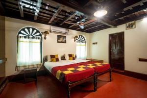 a bedroom with a bed in a room with windows at Emerald Isle in Alleppey