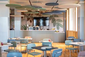 a restaurant with tables and chairs and a counter at H2C Hotel Milanofiori in Assago