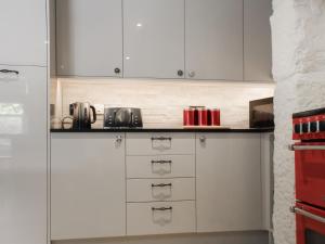 een keuken met witte kasten en rode apparaten bij Mill House - Uk50646 in Stithians