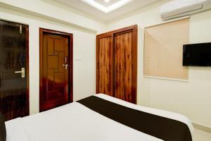 a bedroom with a bed and a tv and a door at Hotel O RS HOTELS in Gachibowli