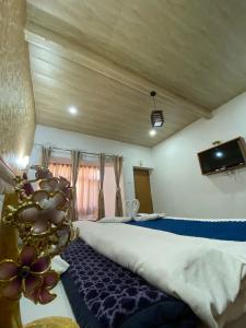 a bedroom with a bed and a tv on the wall at !!The Valley View Hill-Top Heights & Open Rooftop Cafe !! Bonfire !! Family Hotel Near To Mall Road 100Mtr!! in Vashisht