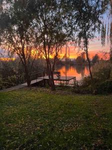 a picnic table and a bench next to a lake at Nyárfás Panoráma Vendégház in Dunavarsány