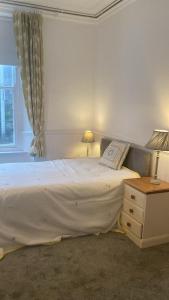 a bedroom with a large white bed and a window at Puffin Apartment in Kingsbridge