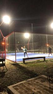 a group of people playing tennis on a court at night at Casa de Lujo de Tenis con Pileta Padel y Gimnasio in Garín
