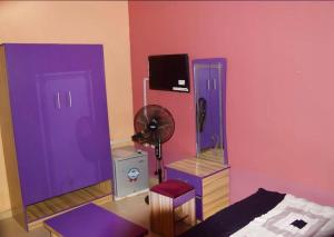 a bedroom with purple doors and a fan at Gracefield hotel & suites in Eggan