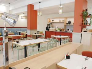 a restaurant with tables and chairs and a kitchen at Mercure Vichy in Vichy
